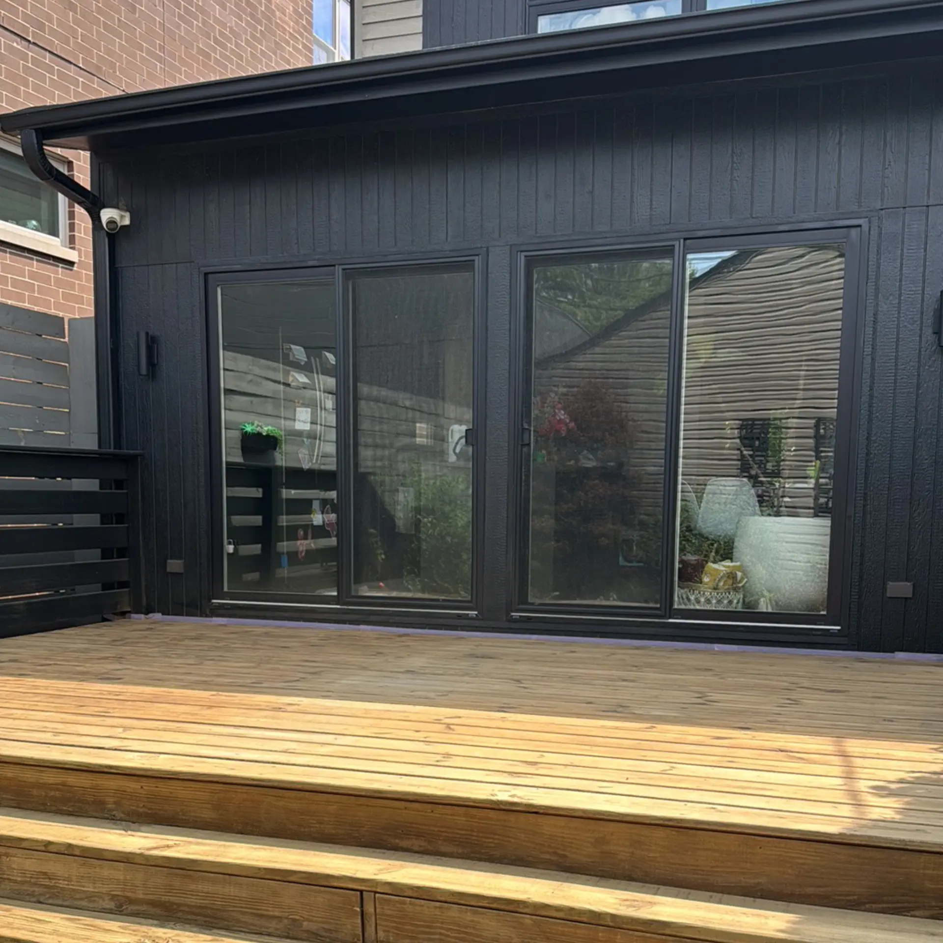 Siding painting in Chicago, IL — dark vertical siding beside a wood deck