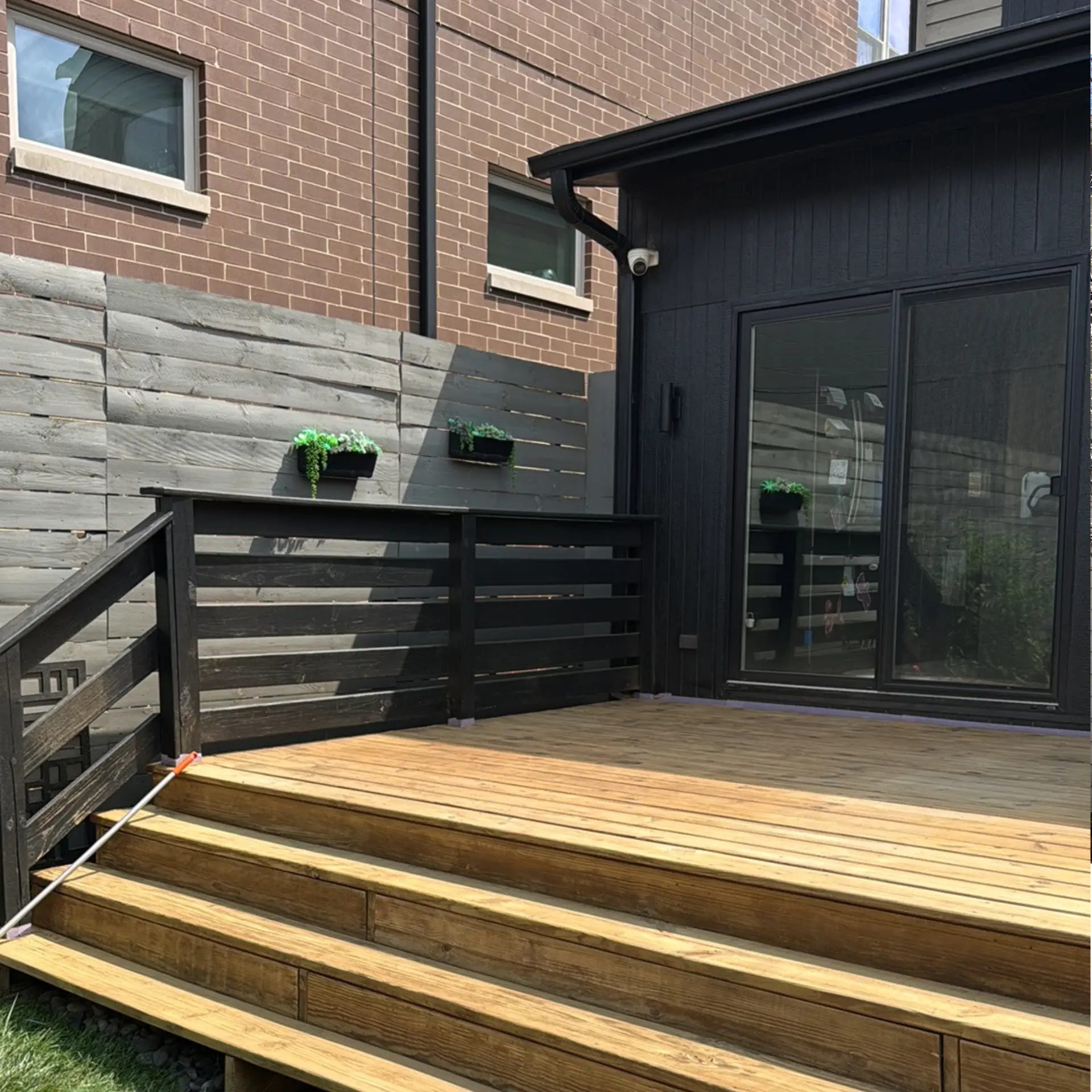 Exterior view showing dark siding, brick and a wood deck